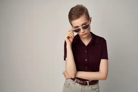 Коротко стриженная женщина в красной рубашке классического стиля на светлом фоне