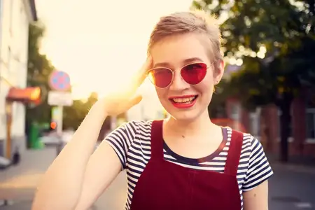 Женщина в солнцезащитных очках гуляет на улице, наслаждаясь свободой и образом жизни