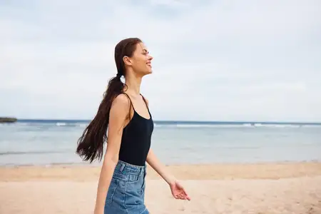 Отдыхающая женщина, молодая, на летних каникулах, занимается активностью на песчаном пространстве пляжа, бежит, улыбается, ощущая счастье моря, телом путешествует, ведет образ жизни, копирует волну…