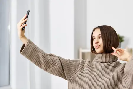 Женщина делает селфи на камеру смартфона дома