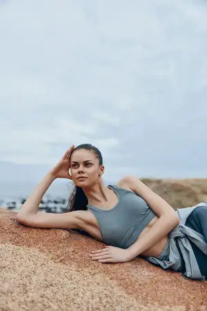 Спортивная женщина в удобной спортивной одежде отдыхает на камнях, излучая уверенность в себе и безмятежность
