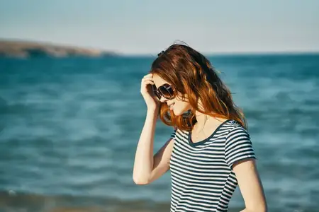 Портрет женщины в очках на фоне моря и гор