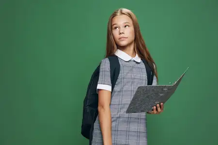 Школьница с рюкзаком в форме держит планшет