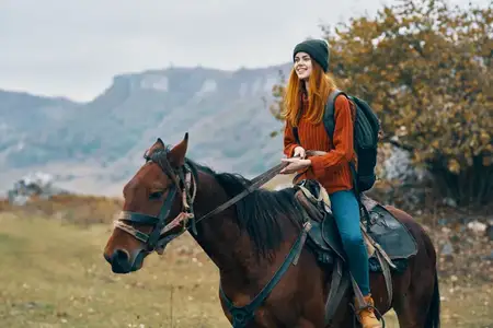 Женщина-туристка едет верхом на лошади в горах, наслаждаясь свежим воздухом