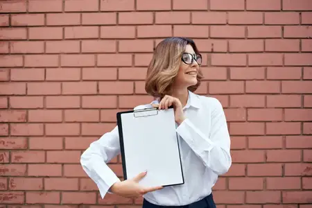 Женщина в белой рубашке с документами, работающая профессионально