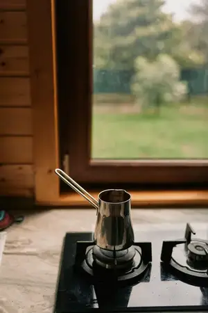 Металлический чайник стоит на газовой горелке в деревянной кухне