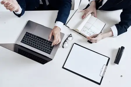 Коллеги работают с ноутбуком и документами на столе