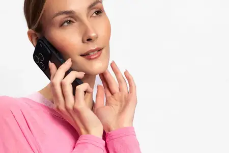 Портрет женщины в розовом топе, прижимающей телефон к уху