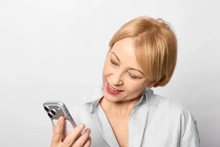Пожилая женщина со смартфоном, общение, улыбка, цифровая переписка, портрет дома, технологии