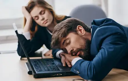 Коллеги по работе спят за столом перед ноутбуком — усталость и отдых