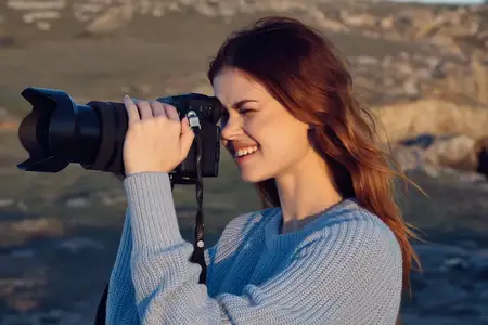 Женщина с фотоаппаратом на природе снимает пейзаж