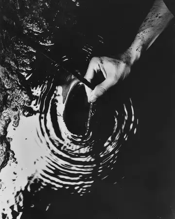 Черно-белое изображение руки, нежно помешивающей воду, создающей круговые круги, символизирующие спокойствие и движение