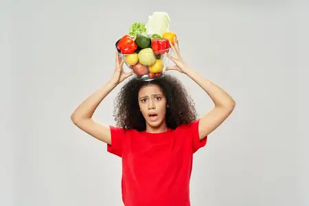 Возмущенная женщина с тарелкой продуктов на голове, крупный план, кадрированный вид