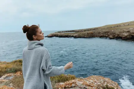 Красивая женщина, свободно гуляющая по каменистому побережью, отдыхающая
