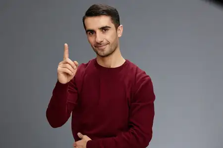 Портрет мужчины, улыбающегося и делающего жест руками в красном свитере на изолированном фоне