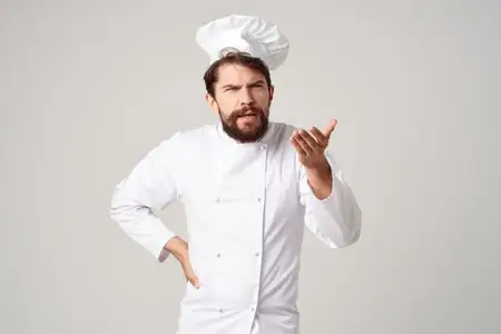 Повар-мужчина на кухне выполняет жесты руками на светлом фоне