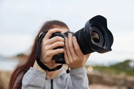 Страстный молодой фотограф запечатлевает моменты с помощью зеркальной камеры в безмятежной обстановке на открытом воздухе, подчеркивая творчество и связь с природой