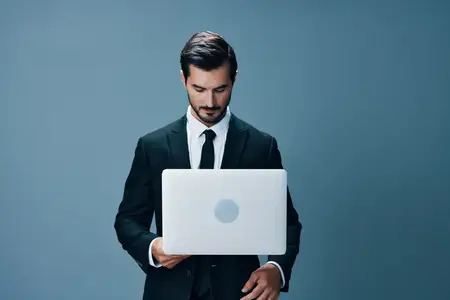 Деловой мужчина в костюме смотрит на свой ноутбук и работает онлайн через интернет, участвуя в видеозвонке на синем фоне