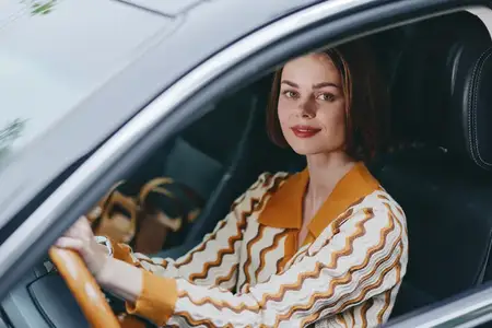 Повседневная мода в теплых тонах, дневная сцена за рулем, расслабленное настроение, акцент на руках на руле и внимательной позе