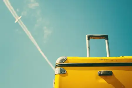 Приключения ждут: путешествуйте стильно с ярким желтым чемоданом рядом с взлетающим реактивным самолетом