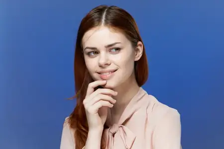Красивая женщина с привлекательным взглядом в шикарной рубашке на синем изолированном фоне