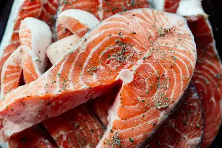 Маринованная красная рыба на тарелке, приготовление морепродуктов, деликатес