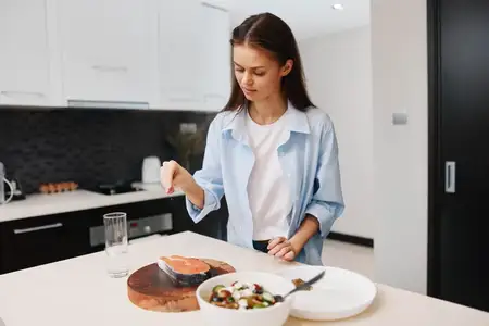 Красивая молодая женщина готовит полезную еду на кухне дома