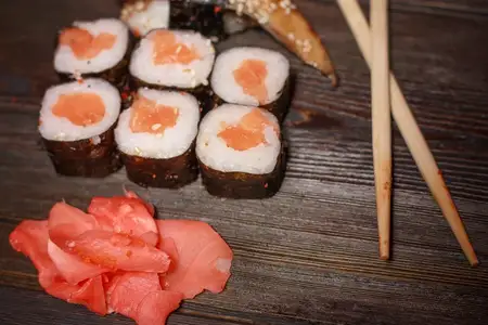 Азиатская кухня: роллы суши, деревянные палочки, васаби, имбирь, морепродукты