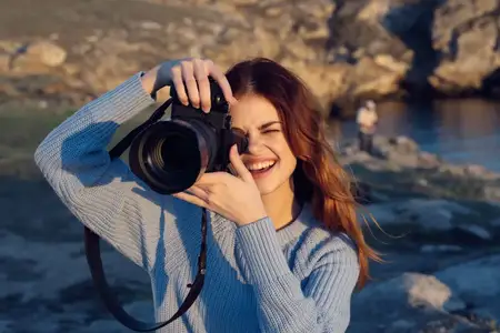 Веселая женщина-фотограф на фоне скалистых гор, пейзаж, отдых на природе