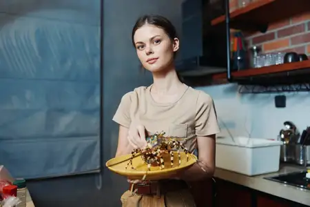 Женщина держит тарелку с едой на кухне, на стойке стоит миска с едой