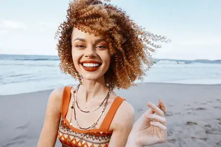 Улыбающаяся женщина с рюкзаком наслаждается счастливым отпуском на пляже