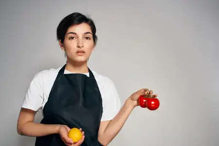 Веселая домохозяйка в черных фартуках, овощи, приготовление еды