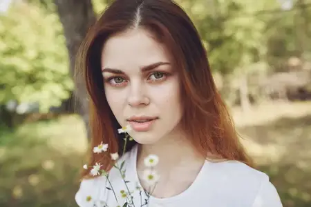 Жизнерадостная женщина держит цветы, олицетворяя солнце, свободу и путешествия