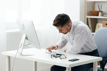 Менеджер работает за компьютером в интернете, демонстрируя уверенность и деловой настрой в офисе