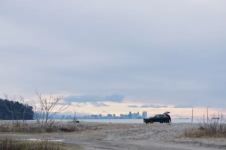 Автомобиль стоит на песчаном пляже с наступлением вечера