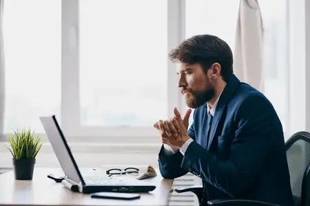 Мужчина в деловом костюме работает перед ноутбуком, демонстрируя профессионализм в сфере технологий