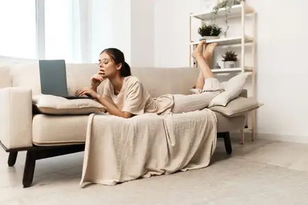 Улыбающаяся женщина печатает на ноутбуке в уютном домашнем офисе, ведущая фриланс-образ жизни