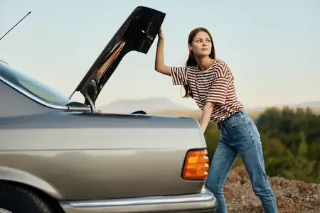 Женщина-водитель открыла багажник автомобиля с озабоченным видом