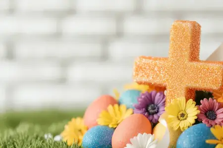 Яркая пасхальная сцена с красочными украшенными яйцами, веселыми цветами и ярким оранжевым крестом на травянистом фоне, символизирующая радостное весеннее празднование