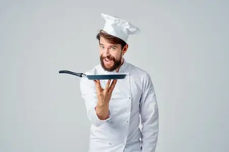 Мужчина в поварской форме с кухонными принадлежностями, работа, светлый фон