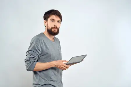 Мужчина с планшетом в руке, интернет-технологии, общение, серая куртка, светлый фон