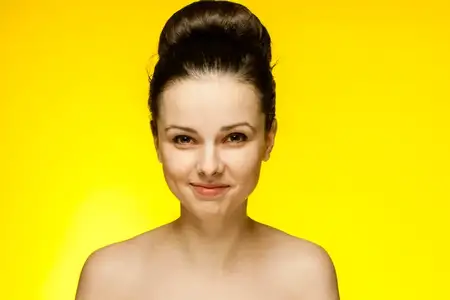 Красивая женщина с обнаженными плечами, улыбка, чистая кожа, желтый фон
