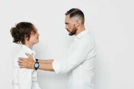 Уверенное, сосредоточенное профессиональное выражение лица появляется, когда руки лежат на плечах в уважительном жесте, раскрывая доверие, руководство и сильную коммуникацию