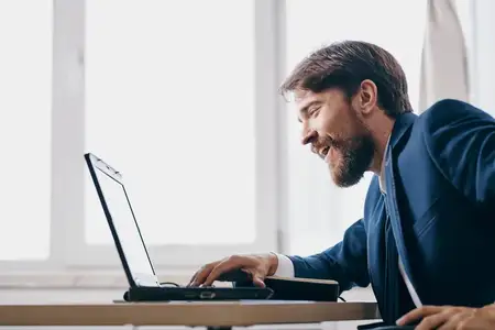 Мужчина работает за ноутбуком в офисе, испытывая эмоции, связанные с интернет-профессионалом