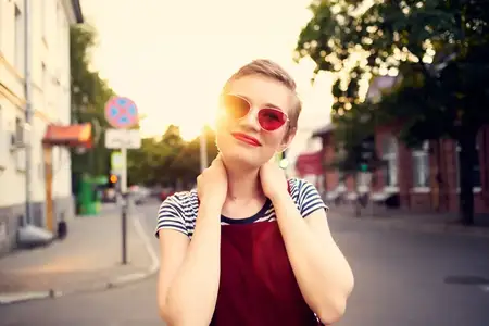 Улыбающаяся женщина в модных солнцезащитных очках наслаждается свежим воздухом во время прогулки