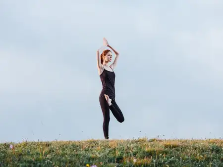 Стройная женщина в леггинсах и футболке занимается йогой на природе в горах
