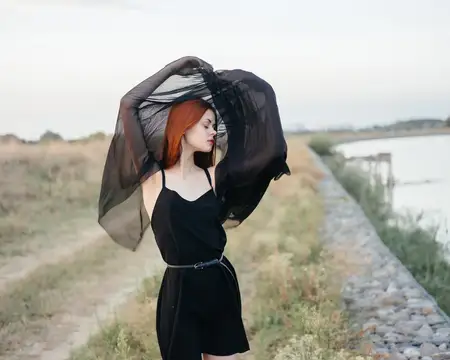 Женщина в черном платье путешествует на природе, демонстрируя модный образ