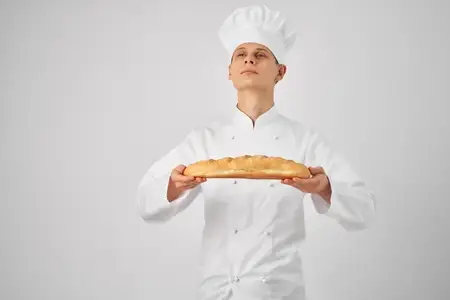 Мужчина в одежде повара, профессионал, держит в руках багет, свежий продукт, работа