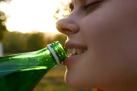 Женщина пьет воду из бутылки, крупный план лица, наслаждение, лето