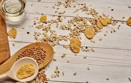 Пшеница и крупа рассыпаны на столе, рядом деревянные ложки и кухонная доска